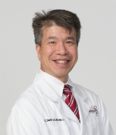 A man in white lab coat and red tie.