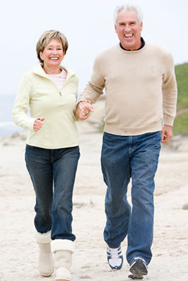 A man and woman holding hands while walking on the beach.